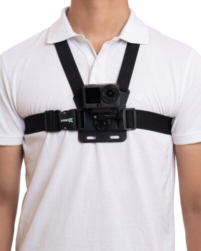 Person wearing a chest-mounted action camera on a black harness over a white shirt.