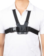 Close-up of a torso wearing a black chest strap harness over a white shirt, with a rectangular front plate and shoulder straps (ARIES logo visible).