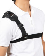 Close-up of a black shoulder strap brace with adjustable buckles worn over a white shirt, labeled ARIES on the tag
