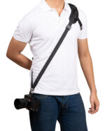 Person wearing a white polo shirt with a black camera strap diagonally across the chest and a camera hanging at the hip/waist area.
