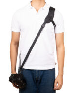 Person wearing a white polo with a crossbody camera strap and camera hanging at the side, ready to shoot