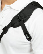 Close-up of a black backpack chest strap and shoulder strap worn over a white shirt.