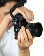Close-up of a person holding a Sony DSLR camera with a large telephoto lens and a strap over the hand.