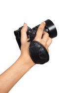 Hands gripping a black DSLR camera with a large lens against a white background.